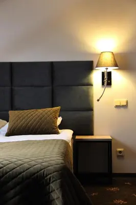 a hotel room with a bed and a lamp at Senoji užeiga in Molėtai