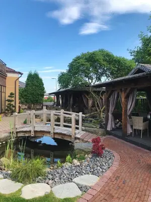 a wooden bridge over a pond in a garden at Senoji užeiga in Molėtai