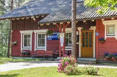 a red cabin with a yellow door and benches at Camping Mindunai in Mindūnai