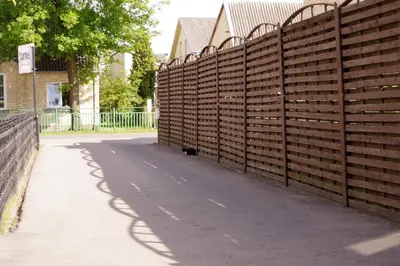 a wooden fence next to a sidewalk and a road at Turnė Guest House in Šiauliai