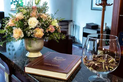 a table with a wine glass and a book and flowers at Hotel Violeta in Druskininkai
