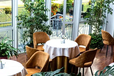 a room with tables and chairs and plants at Hotel Violeta in Druskininkai