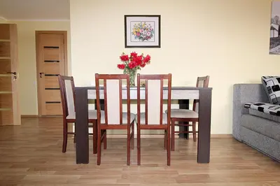 a dining room table with chairs and a vase of flowers at Sauliaus apartamentai in Panevėžys