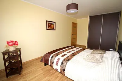 a bedroom with a large bed and a wooden floor at Sauliaus apartamentai in Panevėžys