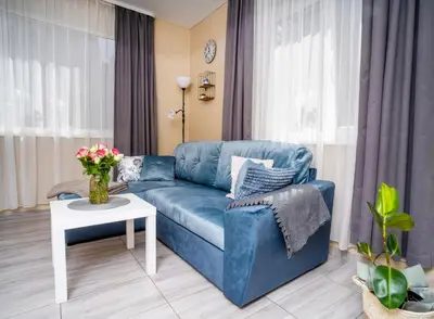 a living room with a blue couch and a table at Cozy Stay Apartment in Kaunas