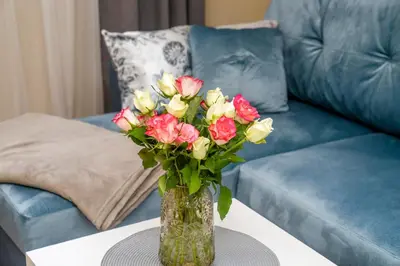 a vase of flowers on a table in front of a couch at Cozy Stay Apartment in Kaunas