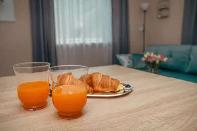 two glasses of orange juice and croissants on a table at Cozy Stay Apartment in Kaunas