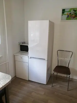 a kitchen with a white refrigerator and a chair at Tėjos guest house in Šiauliai