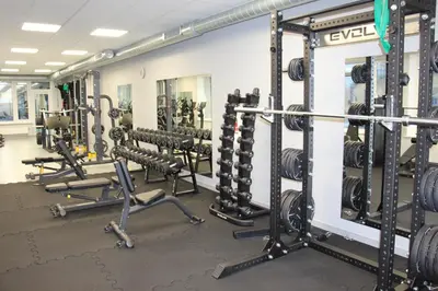 a gym with rows of squat racks and weights at Ignalinos sporto ir pramogų centras in Ignalina