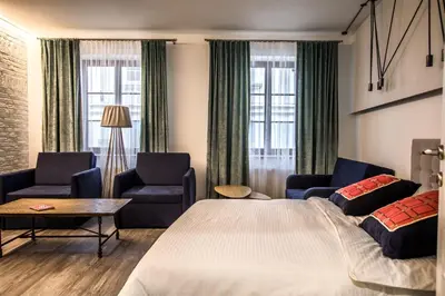 a hotel room with a large bed and two chairs at Dysnos Avenue Apartments in Vilnius
