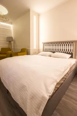 a bedroom with a large white bed and chairs at Dysnos Avenue Apartments in Vilnius