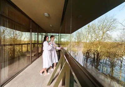 a couple standing on the balcony of a building at Grand SPA Lietuva Serviced Apartments Dzūkija in Druskininkai