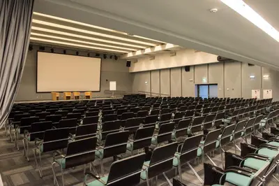 an auditorium with chairs and a white screen at Grand SPA Lietuva Serviced Apartments Dzūkija in Druskininkai