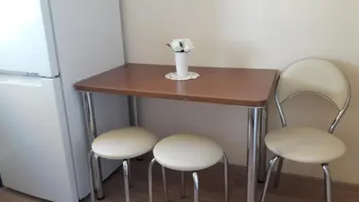 a small table with three chairs and a vase with flowers on it at Tulpių apartamentai in Panevėžys