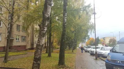 a person walking down a sidewalk next to parked cars at Apartamentai Vilniaus Street in Šiauliai
