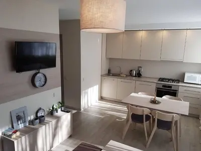 a kitchen with a table and chairs and a clock on the wall at Apartamentai Vilniaus Street in Šiauliai
