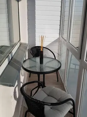 a glass table and chairs on a balcony at Apartamentai Centras in Šiauliai