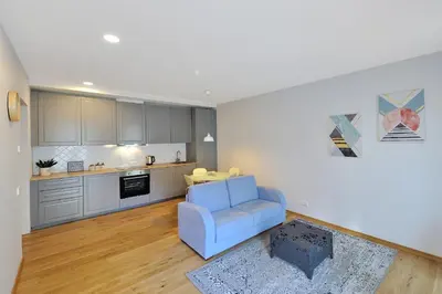 a living room with a blue chair and a kitchen at Cosy 1BD Apartment in Old Town by Domvia in Kaunas