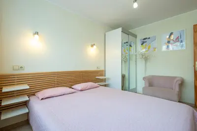 a bedroom with a bed with pink pillows and a chair at Du draugai 1 in Druskininkai