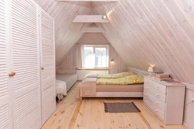 a attic bedroom with a bed and a window at White Cottage in Druskininkai