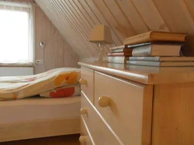 a bedroom with a bed and a dresser with books at White Cottage in Druskininkai