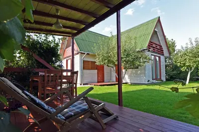 a deck with a chair and a house at White Cottage in Druskininkai