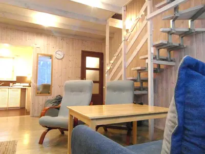 a living room with a table and chairs and stairs at White Cottage in Druskininkai