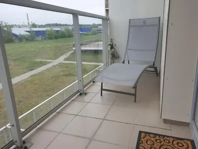a chair on a balcony with a view of a field at Garden Studio by the Lake with Air-Con and Infrasauna in Druskininkai