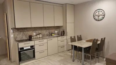 a kitchen with white cabinets and a table with chairs at Garden Studio by the Lake with Air-Con and Infrasauna in Druskininkai