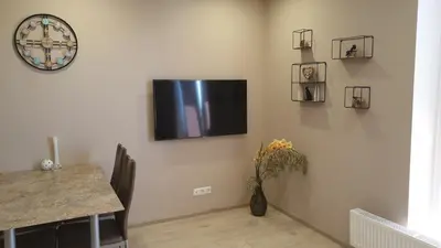 a living room with a tv on a wall with a table at Garden Studio by the Lake with Air-Con and Infrasauna in Druskininkai