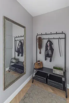 a mirror on a wall next to a shelf with clothes at Avenue in Šiauliai
