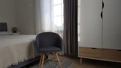 a bedroom with a chair next to a bed and a window at Centro apartamentai in Birštonas
