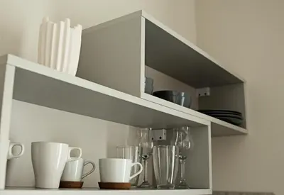 a white shelf with cups and utensils on it at Centro apartamentai in Birštonas