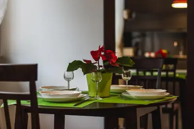 a table with plates and a vase with a red flower at MOCHA HOUSE 3 ROOM CENTRAL APARTMENT 56d in Kaunas