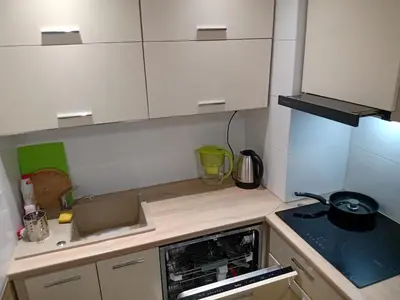 a small kitchen with white cabinets and a stove at forest-house lt in Druskininkai