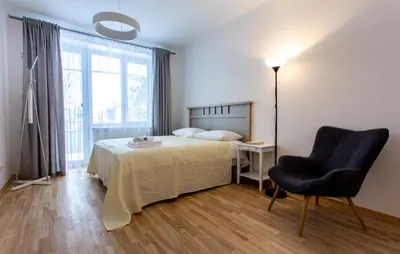 a bedroom with a bed and a chair and a lamp at Violetos Lux Apartamentai2 in Druskininkai
