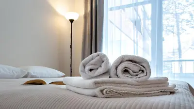 a pile of towels sitting on top of a bed at Violetos Lux Apartamentai2 in Druskininkai