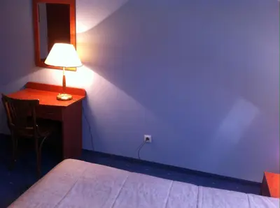 a bedroom with a bed and a desk with a lamp at Guest House Guba in Molėtai