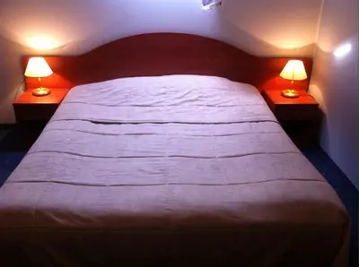 a bedroom with a large bed with two lamps at Guest House Guba in Molėtai