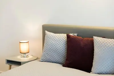 a bed with pillows and a lamp on a table at Relax Birstonas in Birštonas