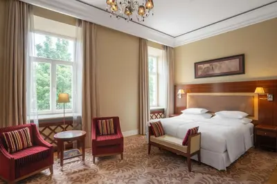 a hotel room with a bed and two chairs at Grand Hotel Vilnius, Curio Collection by Hilton in Vilnius
