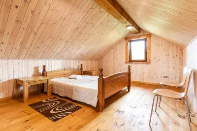 a bedroom with a bed and a chair in a attic at Vip Forest dreams villa in Anykščiai