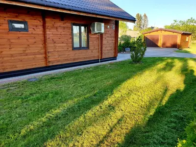 a house with a grassy yard next to a building at Holiday House & Sauna in Druskininkai in Neravai