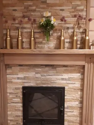 a fireplace with gold vases on top of it at Holiday House & Sauna in Druskininkai in Neravai