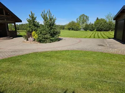 a walkway leading to a building with a grassy field at Holiday House & Sauna in Druskininkai in Neravai
