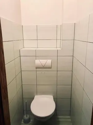 a bathroom with a toilet with a white tiled wall at Welcoming apartment in Anykščiai
