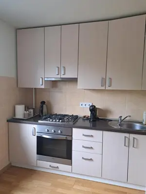 a kitchen with white cabinets and a stove and a sink at Welcoming apartment in Anykščiai