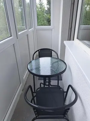 a table and two chairs in a room with windows at Welcoming apartment in Anykščiai