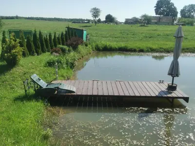 a dock with a bench and an umbrella in a pond at Edmart in Dobromislė