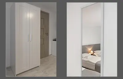 a white bedroom with a bed and a mirror at HappyInn Rooms in Kaunas